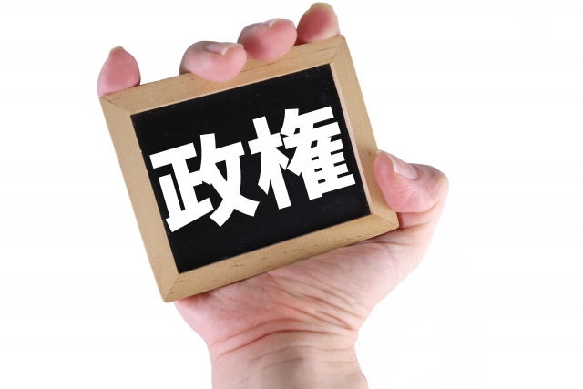 「政権」と書かれた小さい板を握る手の部分